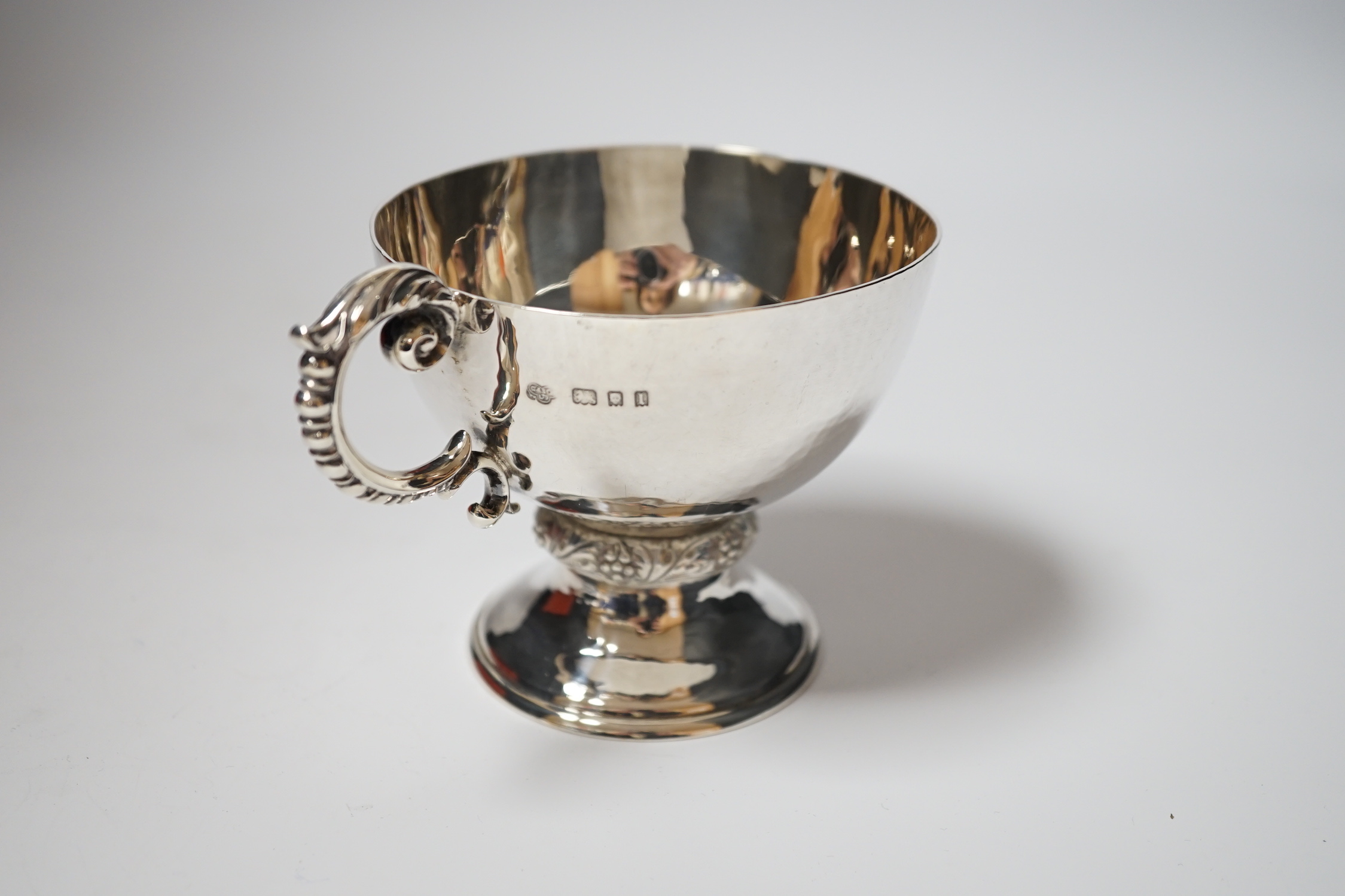 A George V planished silver pedestal single handled cup, Goldsmiths & Silversmiths Co Ltd, London, 1926, 86mm, 5.9oz.